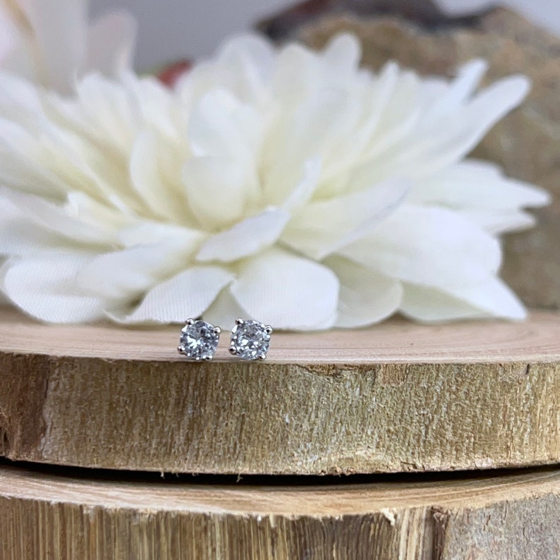 May include: A pair of silver stud earrings with clear round cubic zirconia stones.