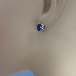 Puede incluir: Un pendiente de plata con una piedra preciosa azul. El pendiente es de estilo de bot&oacute;n y est&aacute; engastado en un dise&ntilde;o simple y elegante.