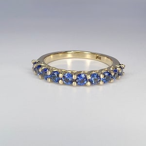 May include: A gold band ring with a row of blue sapphires.