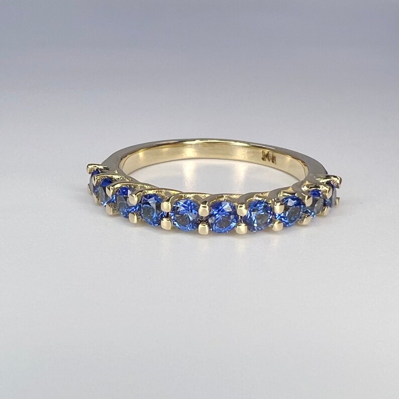 May include: A gold band ring with a row of blue sapphires.