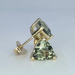 May include: A gold earring with a green gemstone set in a triangular shape. The earring has a post and butterfly back.