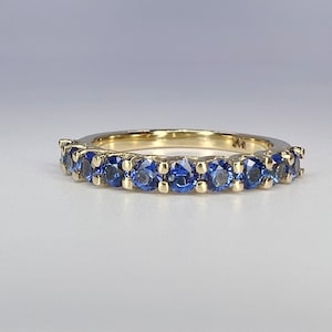 May include: A gold band ring with a row of blue sapphires.