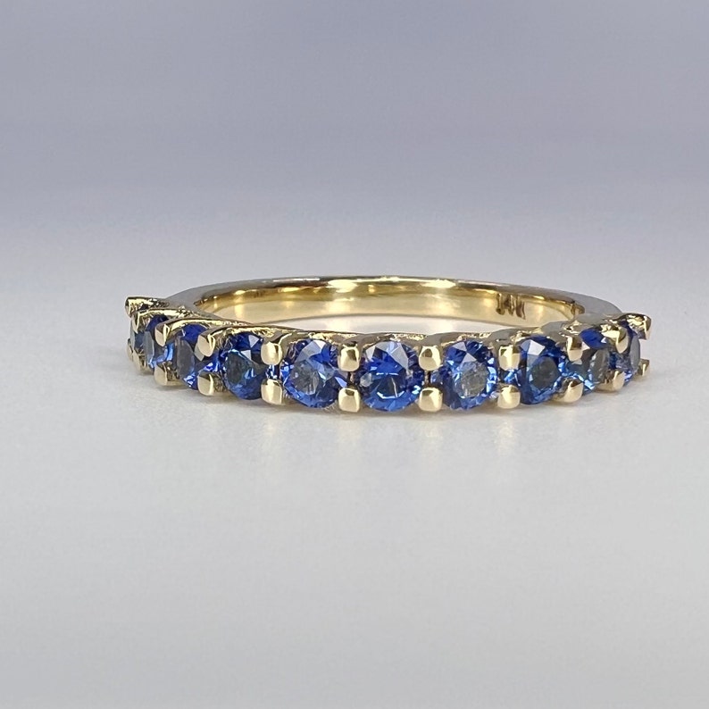 May include: A gold band ring with a row of blue sapphires.