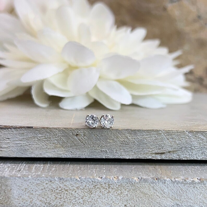 May include: A pair of silver stud earrings with clear round gemstones.