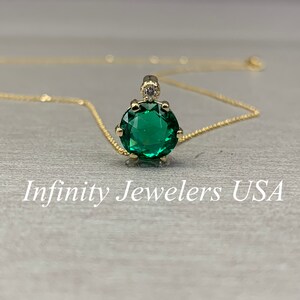 May include: A gold chain necklace with a green gemstone pendant. The pendant is round and has a small diamond accent at the top.