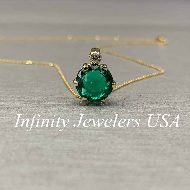 May include: A gold chain necklace with a green gemstone pendant. The pendant is round and has a small diamond accent at the top.