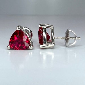 May include: A pair of silver earrings with red triangular gemstones. The earrings have a post and butterfly back.