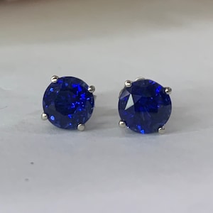 Puede incluir: Un par de pendientes de bot&oacute;n de plata con piedras redondas de color azul oscuro.