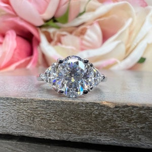May include: A silver ring with a large oval-shaped center stone and two smaller pear-shaped stones on either side.