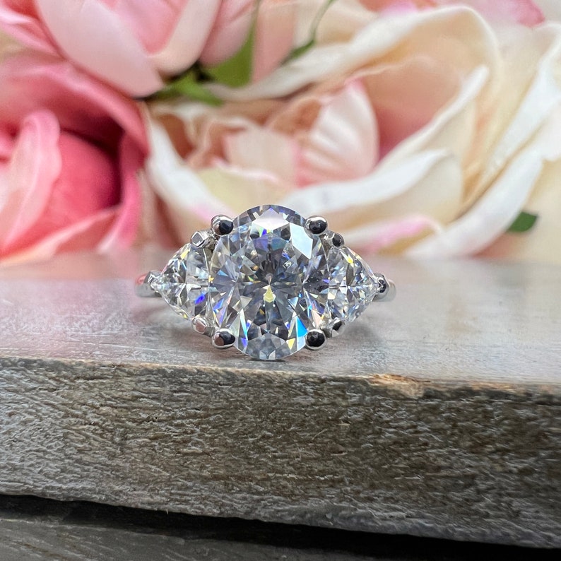 May include: A silver ring with a large oval-shaped center stone and two smaller pear-shaped stones on either side.