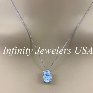 May include: A silver necklace with a large, oval-cut, clear gemstone pendant. The chain is delicate, and the pendant is set in a silver setting. The text "Infinity Jewelers USA" is displayed in white.