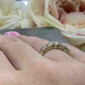 May include: A gold band ring with five round diamonds set in a curved row.