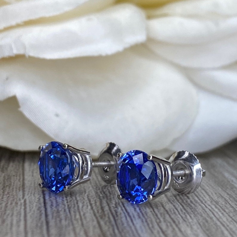 Puede incluir: Un par de pendientes de plata con una piedra preciosa redonda de zafiro azul en cada pendiente.