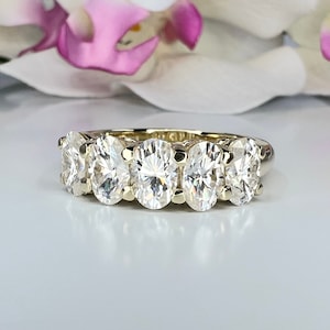 May include: A gold band ring with five oval-shaped diamonds set in a row.