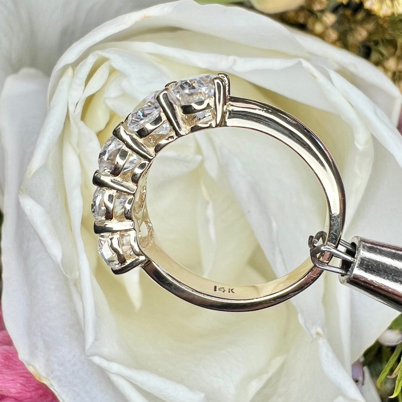 May include: A gold band ring with five round clear stones set in a row. The ring is marked "10K" on the inside.