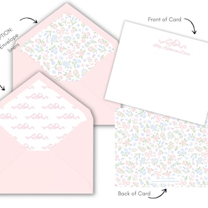 May include: Pink envelope liner with a white background and a pattern of pink ribbons. The back of the card has a white background with a pattern of pink, blue, and green flowers and ribbons. The front of the card is blank with the text "Lily Katherine Davis" in pink.