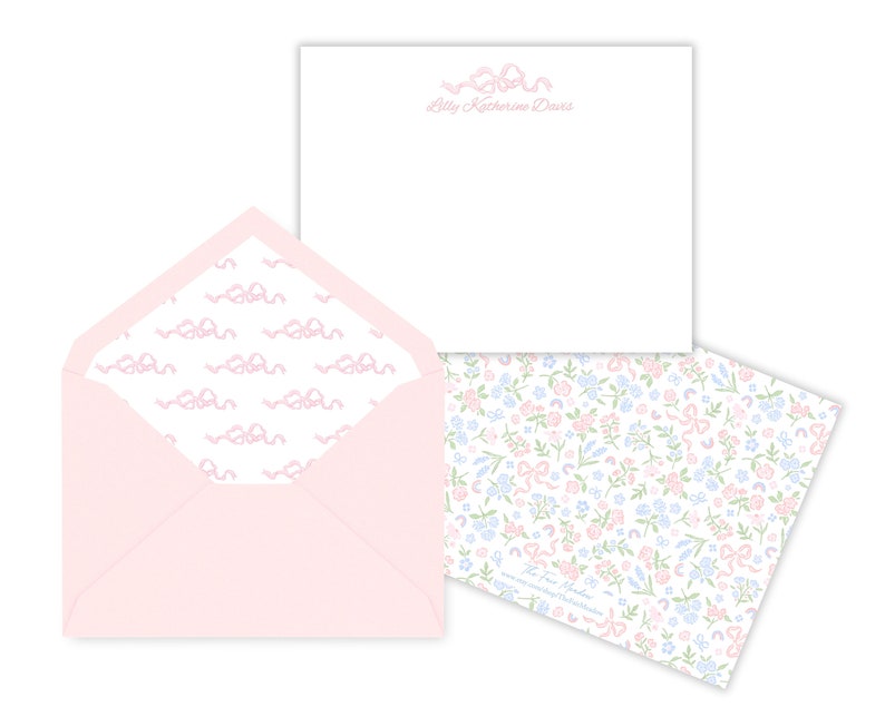 May include: Pink envelope with a white lining featuring a repeating pattern of pink bows. The envelope is open to reveal a white card with the text "Lilly Katherine Davis" in pink script.