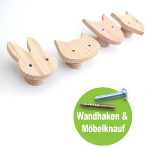 Op de afbeelding: Vier houten wandhaken in de vorm van een kat, een konijn en twee gestileerde dierengezichten. De haken zijn gemaakt van lichtbruin hout en hebben zwarte stippen voor ogen. De haken worden geleverd met twee schroeven, een zilveren en een gouden.