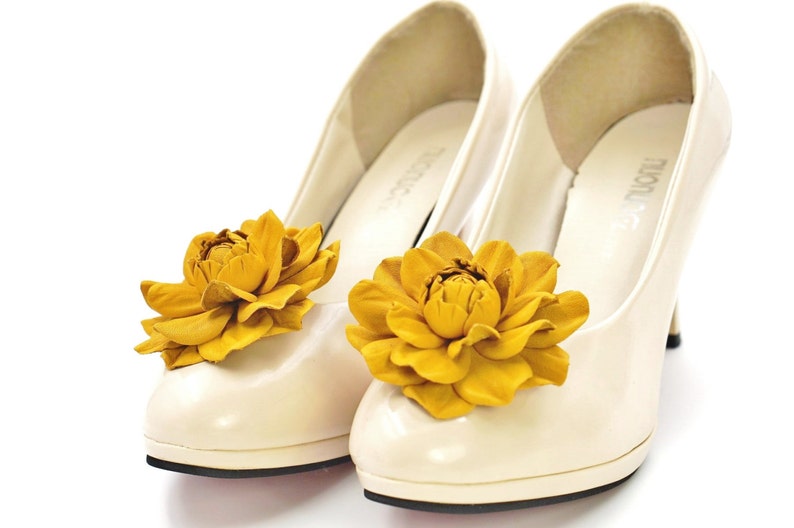 May include: A pair of white high-heeled shoes with yellow flower embellishments.
