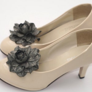K&ouml;nnte beinhalten: Ein Paar beigefarbene High-Heel-Schuhe mit schwarzen Stoffblumenverzierungen.