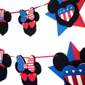 May include: A festive banner featuring black Mickey Mouse silhouettes with patriotic red, white, and blue accents. The banner includes stars, hearts, and bows, perfect for a themed celebration.
