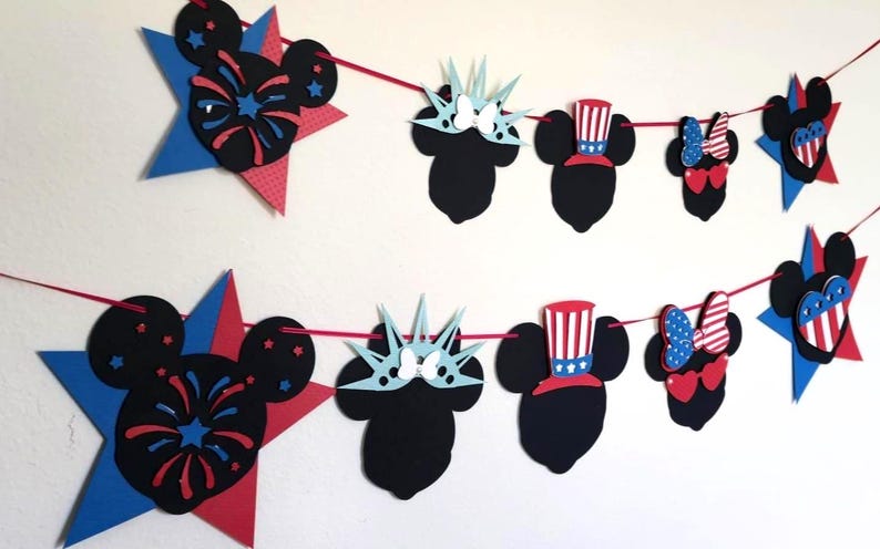 May include: A festive red string garland featuring patriotic Mickey Mouse-themed cutouts. The garland includes Mickey Mouse heads, stars, and other shapes in red, white, and blue, perfect for a themed party or celebration.