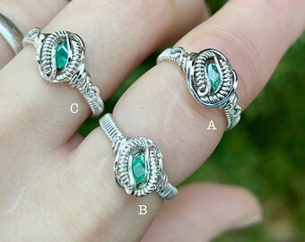 May include: Three silver wire wrapped rings with green gemstones. The rings are labeled A, B, and C.