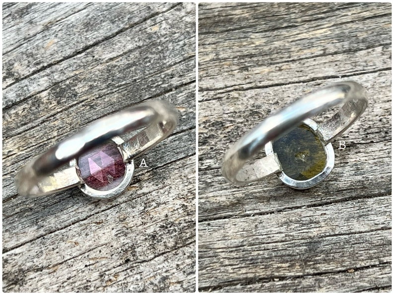 May include: Two silver rings with different gemstones. The ring on the left has a pink gemstone, and the ring on the right has a green gemstone.