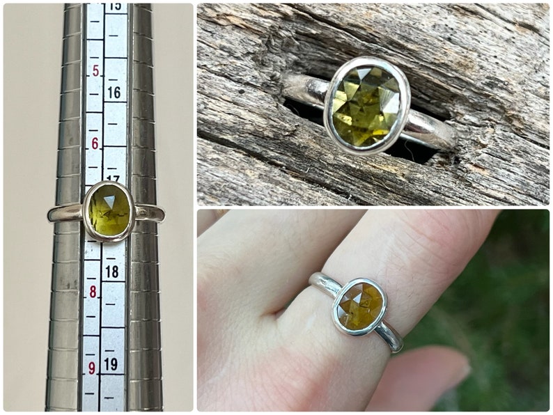 May include: A silver ring with a green oval gemstone. The ring is shown on a finger sizing tool and on a finger.