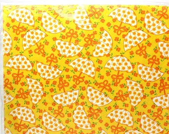 May include: Yellow gift wrap with a pattern of white umbrellas with orange polka dots and orange flowers. The text on the label reads "Gift Wrap Bridal Shower 2 sheets total of 7.9 sq. ft. Each sheet (1.64 ft. x 2.41 ft.) American Greetings."