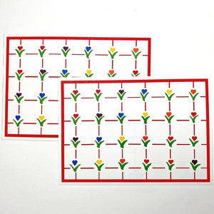 Könnte beinhalten: Zwei rechteckige weiße Karten mit einem roten Gittermuster. Jedes Gitterquadrat enthält einen kleinen grünen Stängel mit einer bunten herzförmigen Blüte in Rot, Blau, Gelb, Lila und Orange, die in einem sich wiederholenden Muster angeordnet sind.