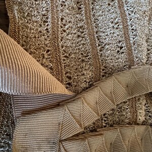 May include: Close-up of beige fabric with a woven, openwork design. The image shows a combination of textures, including a ribbed ribbon and a zigzag-folded ribbon. The color palette is neutral, with shades of beige and tan.