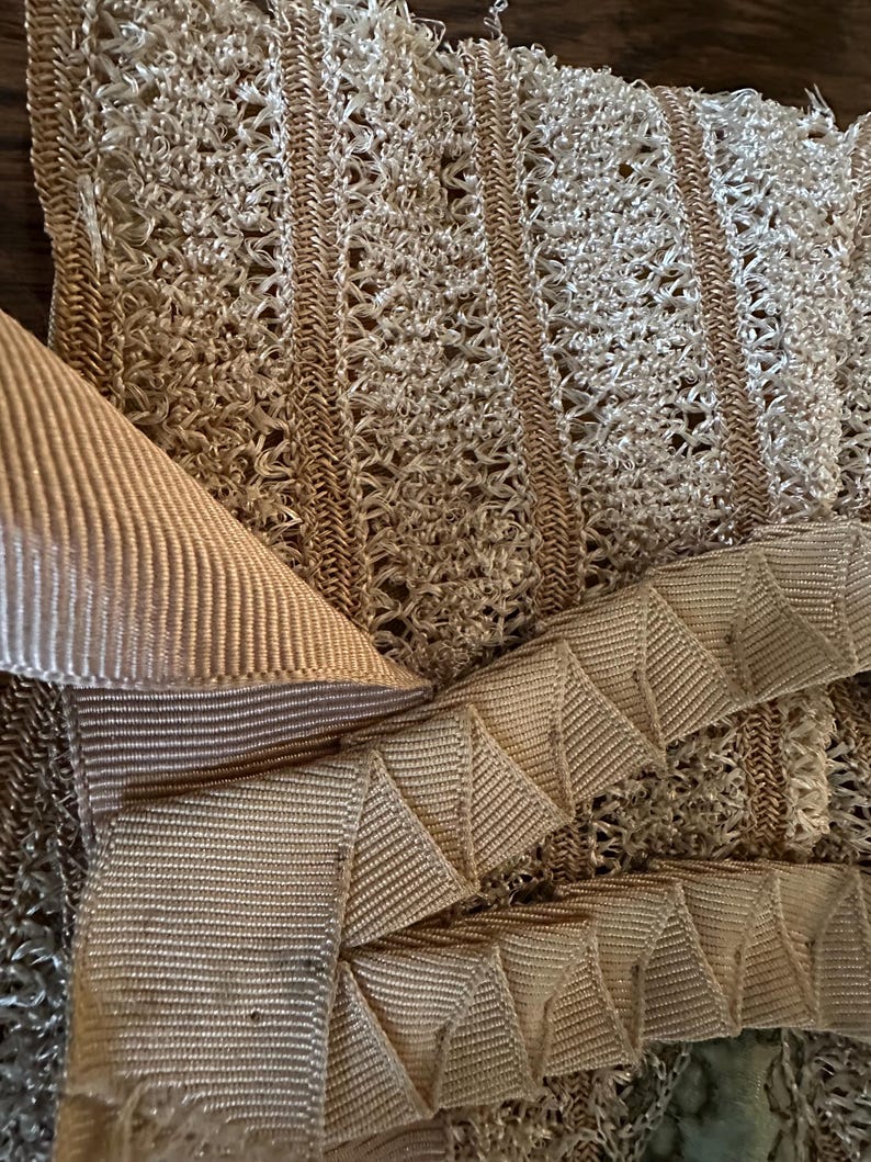May include: Close-up of beige fabric with a woven, openwork design. The image shows a combination of textures, including a ribbed ribbon and a zigzag-folded ribbon. The color palette is neutral, with shades of beige and tan.