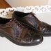 May include: Two brown leather brogue shoes with laces. The shoes have a wingtip design and are on a white surface.