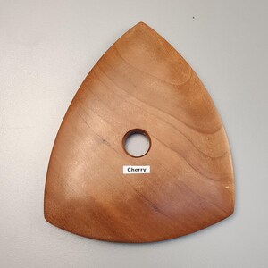 May include: A triangular wooden pottery tool with a hole in the center. The tool is made of cherry wood and has a smooth, polished surface. The word "Cherry" is printed on a white label.