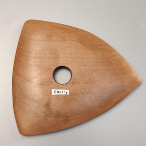 May include: A wooden pottery rib tool with a triangular shape and a circular hole. The tool is a warm brown color and has the word "Cherry" printed on a small white label.