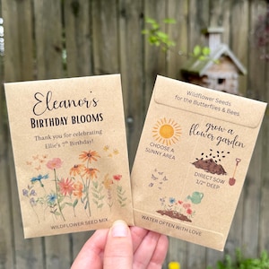 May include: Two seed packets with wildflower themes. One reads "Eleanor's Birthday Blooms" and thanks guests for celebrating Ellie's 7th birthday. The other packet says "Wildflower Seeds for the Butterflies & Bees" and includes planting instructions.