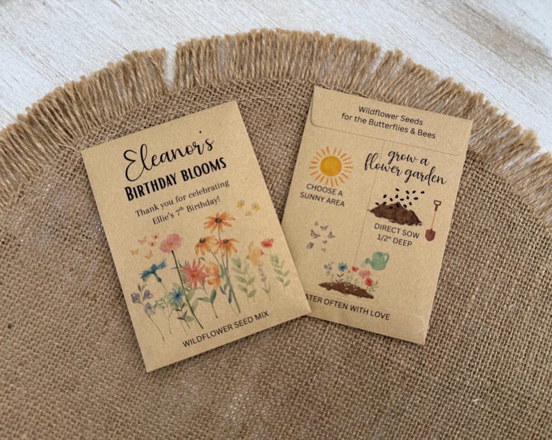 May include: Two brown paper seed packets with floral illustrations and text. One reads "Eleanor's Birthday Blooms" and "Wildflower Seed Mix." The other packet says "Wildflower Seeds for the Butterflies & Bees" and "grow a flower garden."