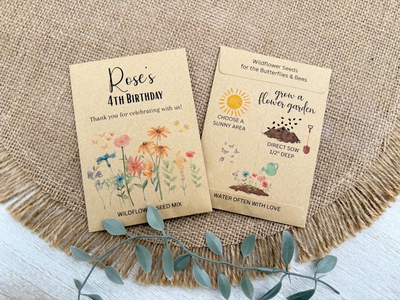 May include: Two seed packets on a burlap surface. One reads "Rose's 4th Birthday" with floral illustrations. The other says "Wildflower Seeds for the Butterflies & Bees" with planting instructions. The packets are tan with black and colorful text and illustrations.