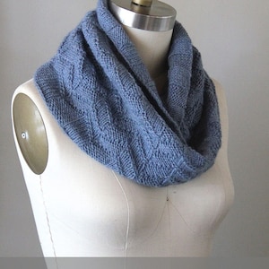 May include: A blue knitted cowl neck scarf with a textured pattern. Knitting Pattern.