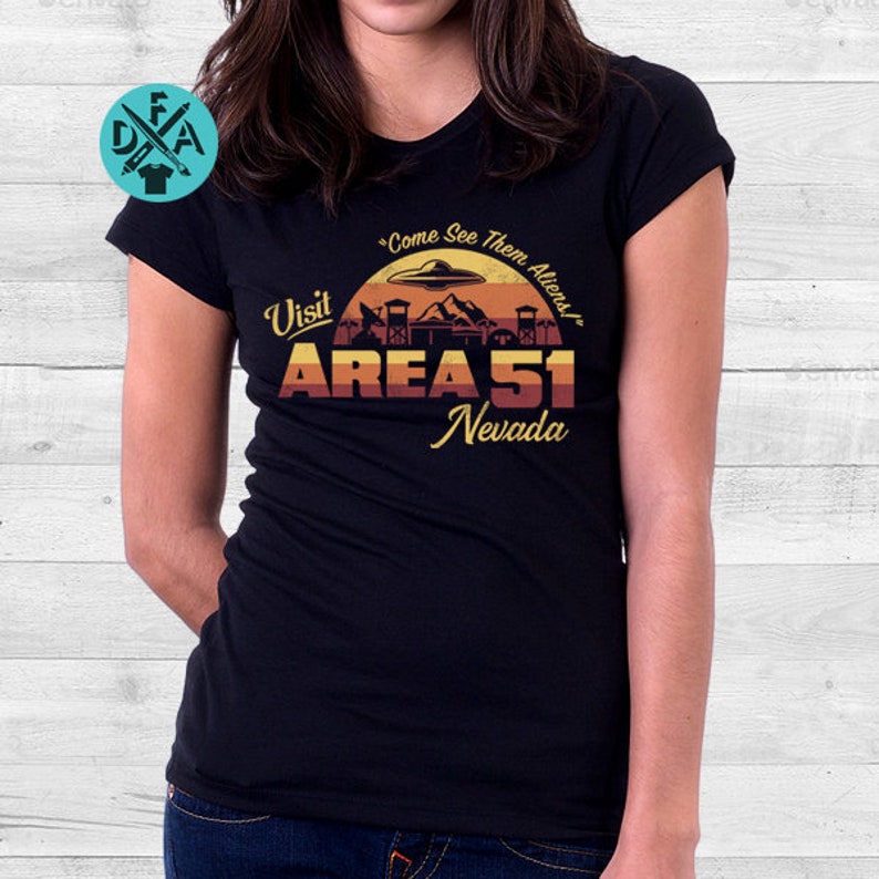 May include: Black t-shirt with a retro-style graphic that says "Visit Area 51 Nevada" with a UFO and a fence. The text also says "Come See Them Aliens!"