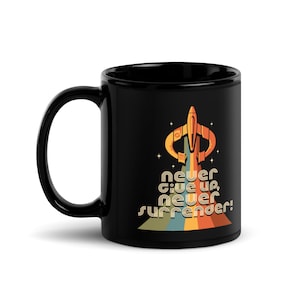 May include: Black ceramic coffee mug with a retro-style spaceship design and the text "never give up, never surrender!" in rainbow colors.