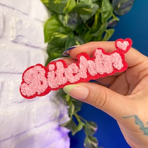 May include: Pink fluffy patch with the word "Bitchen" in red lettering and a small pink heart.