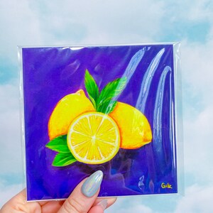 Puede incluir: Una pintura de tres limones sobre un fondo morado. Los limones son amarillos con hojas verdes. La pintura est&aacute; firmada "Gubz" en la esquina inferior derecha.