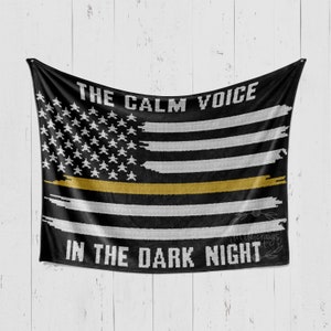 May include: Black and white American flag with a thin gold stripe across the middle. The text "THE CALM VOICE IN THE DARK NIGHT" is printed on the flag.