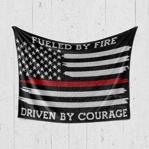 May include: Black and white American flag with a red stripe across the middle. The flag has the words "Fueled by Fire" at the top and "Driven by Courage" at the bottom.