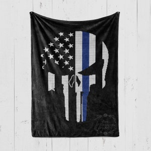 Könnte beinhalten: Schwarze Fleece-Decke mit einer weiß-blauen amerikanischen Flagge und einem blauen Linienmuster in Form eines Spartanerhelms. Die Decke trägt den Text "Two Little Craigs Crochet" in einem Kreis unten.