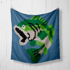 May include: A green and black pixelated fish design on a blue crocheted throw blanket.