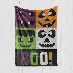 May include: A crocheted blanket with a Halloween theme. The blanket features four different faces: a vampire, a pumpkin, Frankenstein, and a skull. The blanket also has the word "BOO!" written on it.