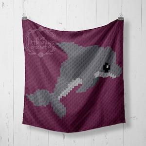 May include: A crocheted blanket with a gray dolphin design on a burgundy background. The blanket features the text "two little craigs crochet" in white.